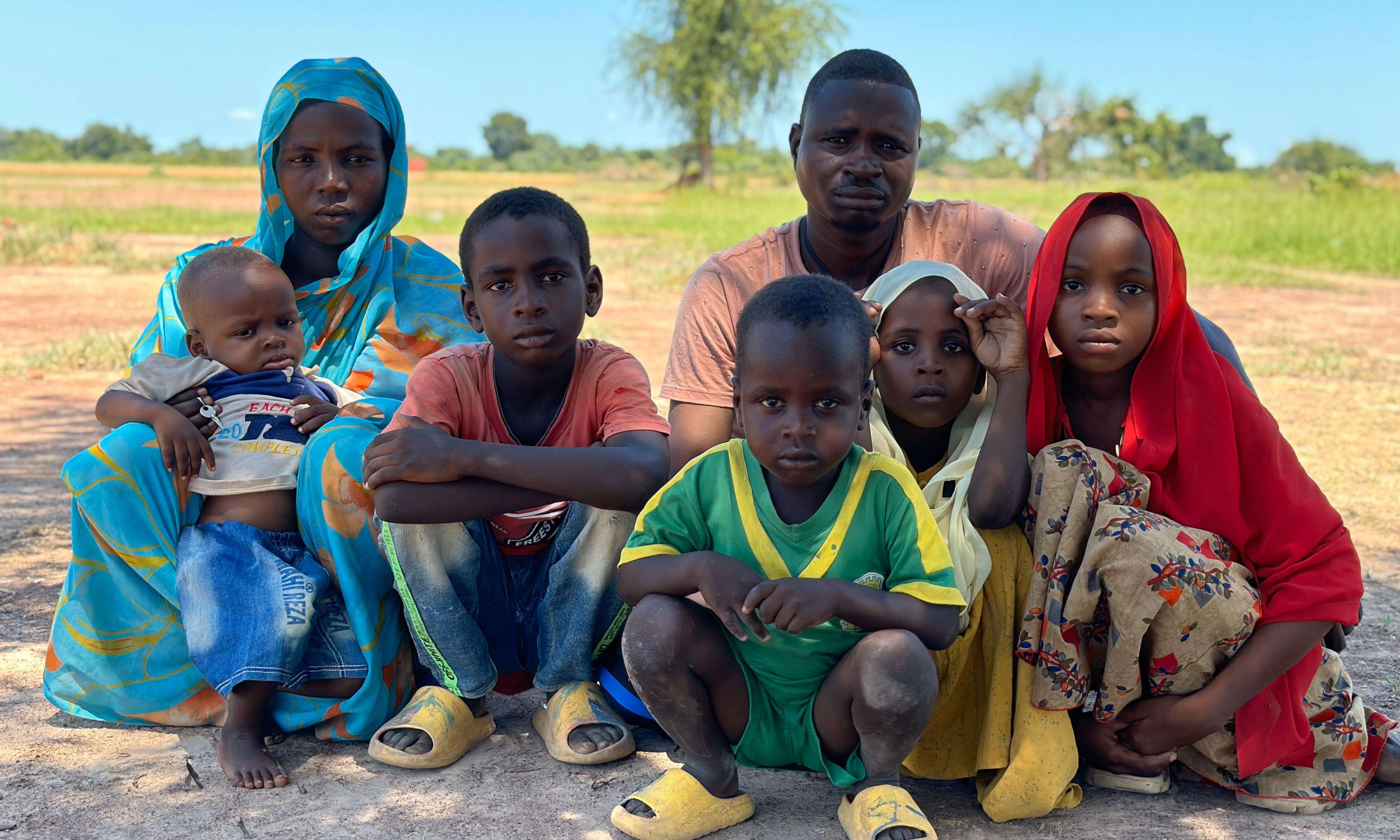 A refugee family from Sudan sits on the grass outside Wedweil camp in South Sudan.