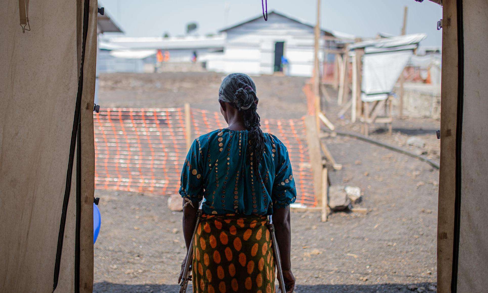 A woman stands in a makeshift tent facing away in a camp for displaced people near Goma, Democratic Republic of Congo.