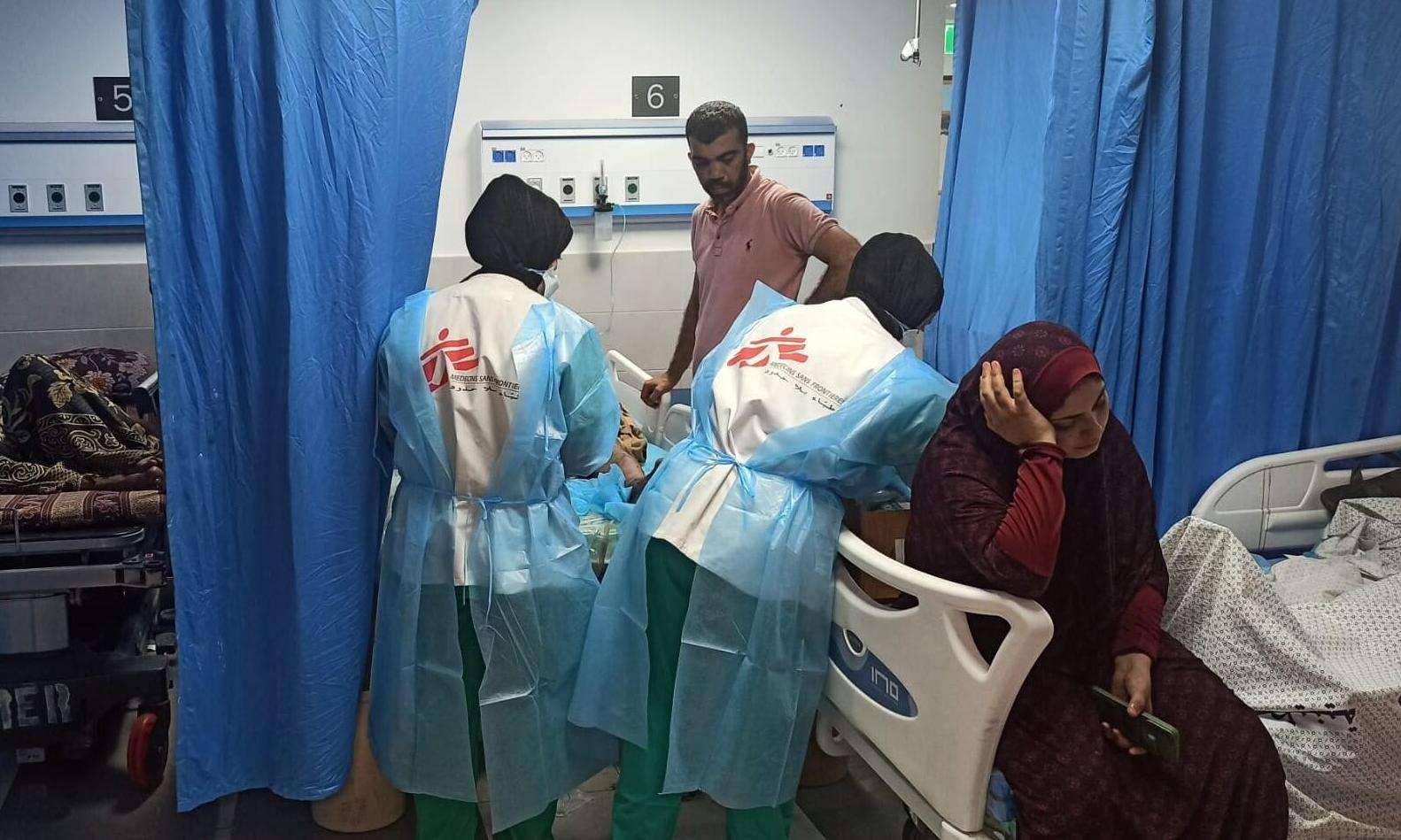 MSF teams treat a patient at al Shifa Hospital while a woman sits in the next bed.
