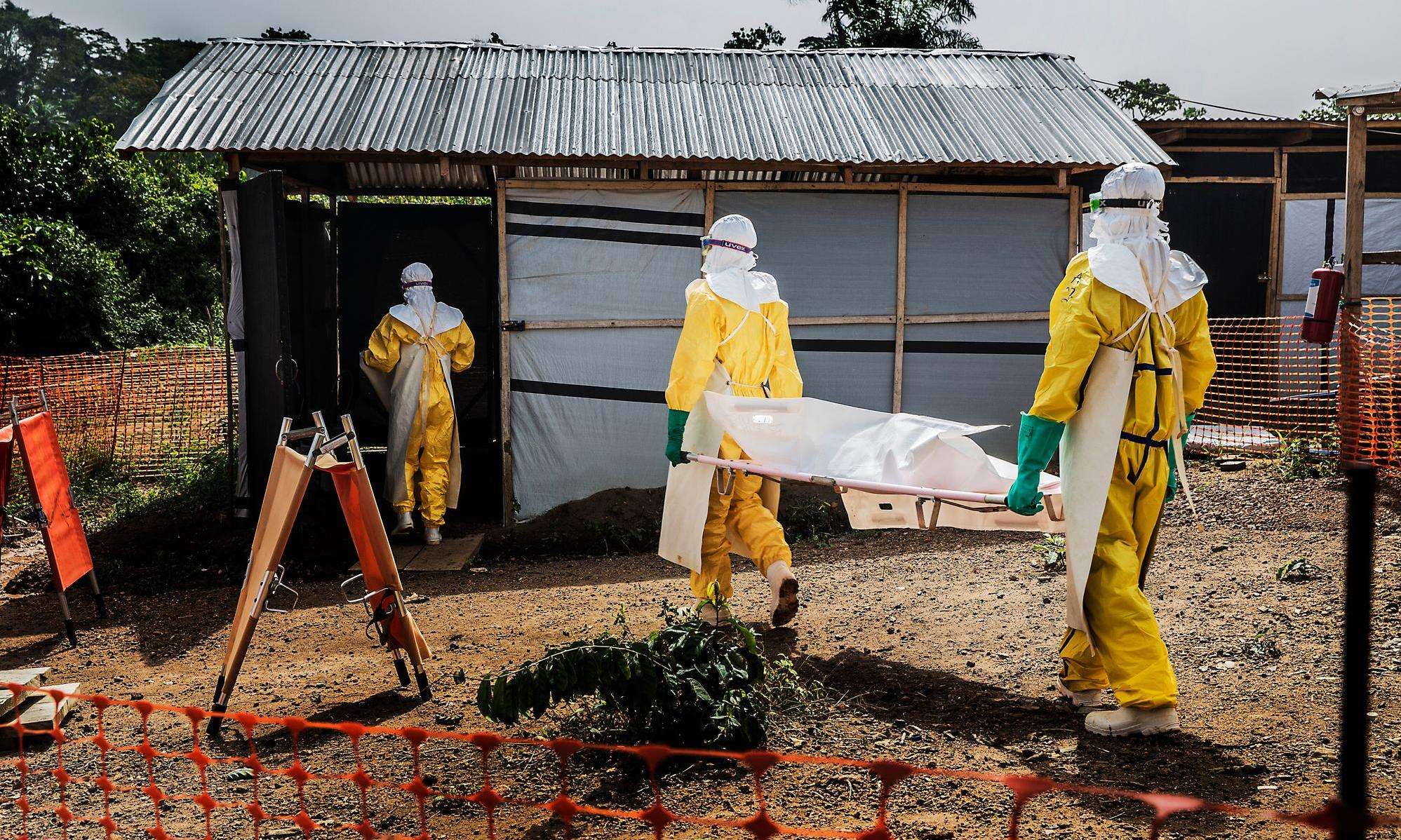 MSF staff members carry a deceased Ebola patient to the morgue in Kailahun, Sierra Leone. 