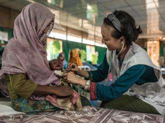 A health worker tends to a young patient at the MSF hospital in Goyalmara, Cox's Bazar, Bangladesh.
