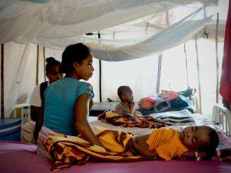 Mother sits beside her child receiving treatment for malaria.