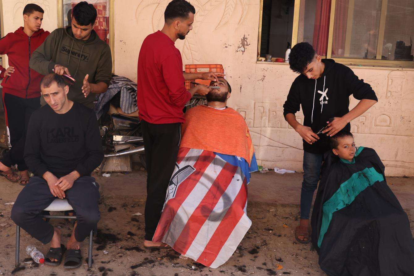 Barbers trim the hair of displaced people at a displacement site in Gaza.
