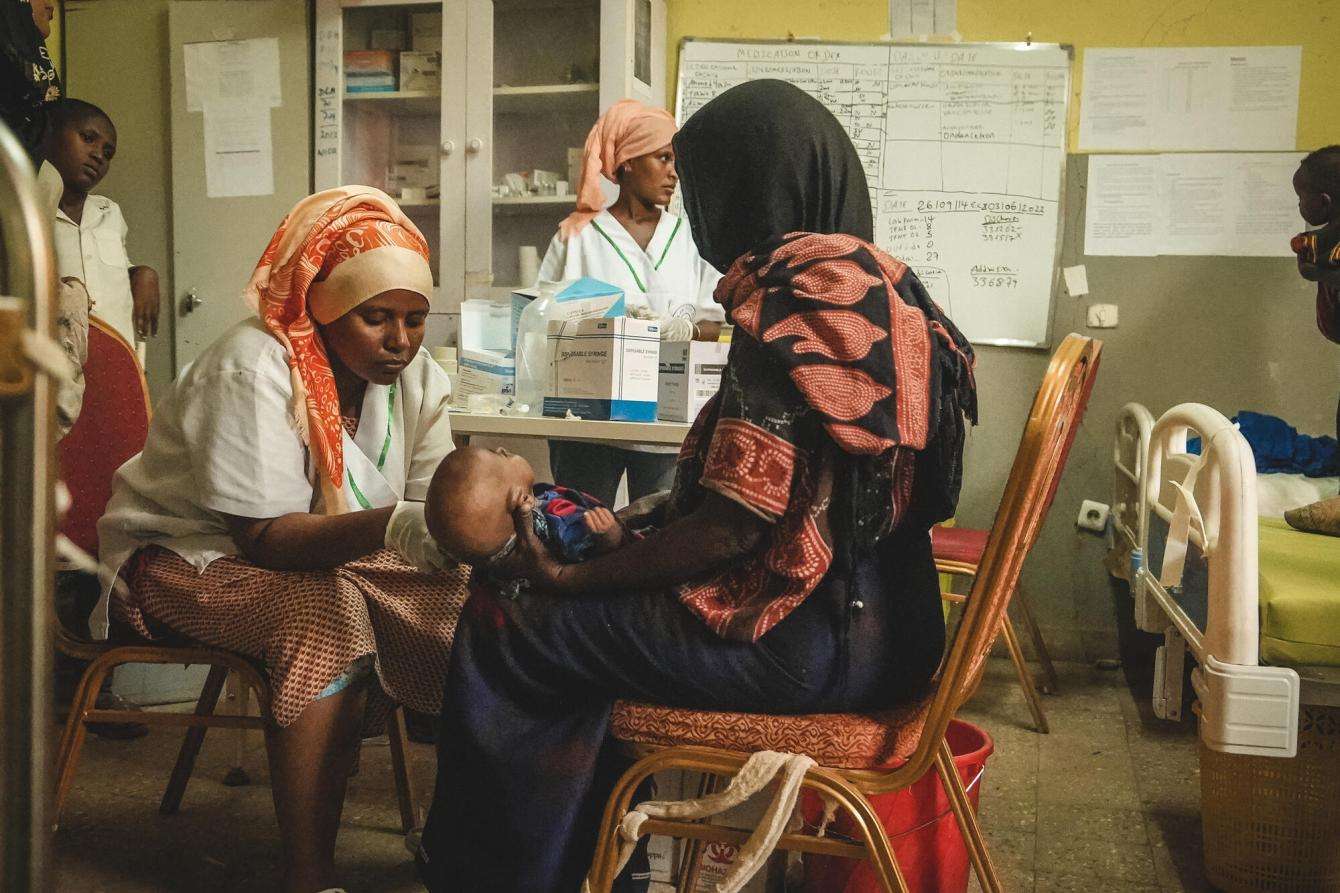 MSF aid worker treats child on mother's lap in Ethiopia during nutritional crisis in Afar region