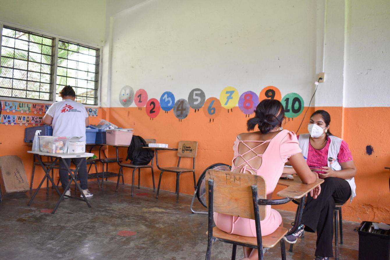A doctor from the Choloma mobile team provides a follow-up consultation to a client in a classroom at the Los Caraos community school. 