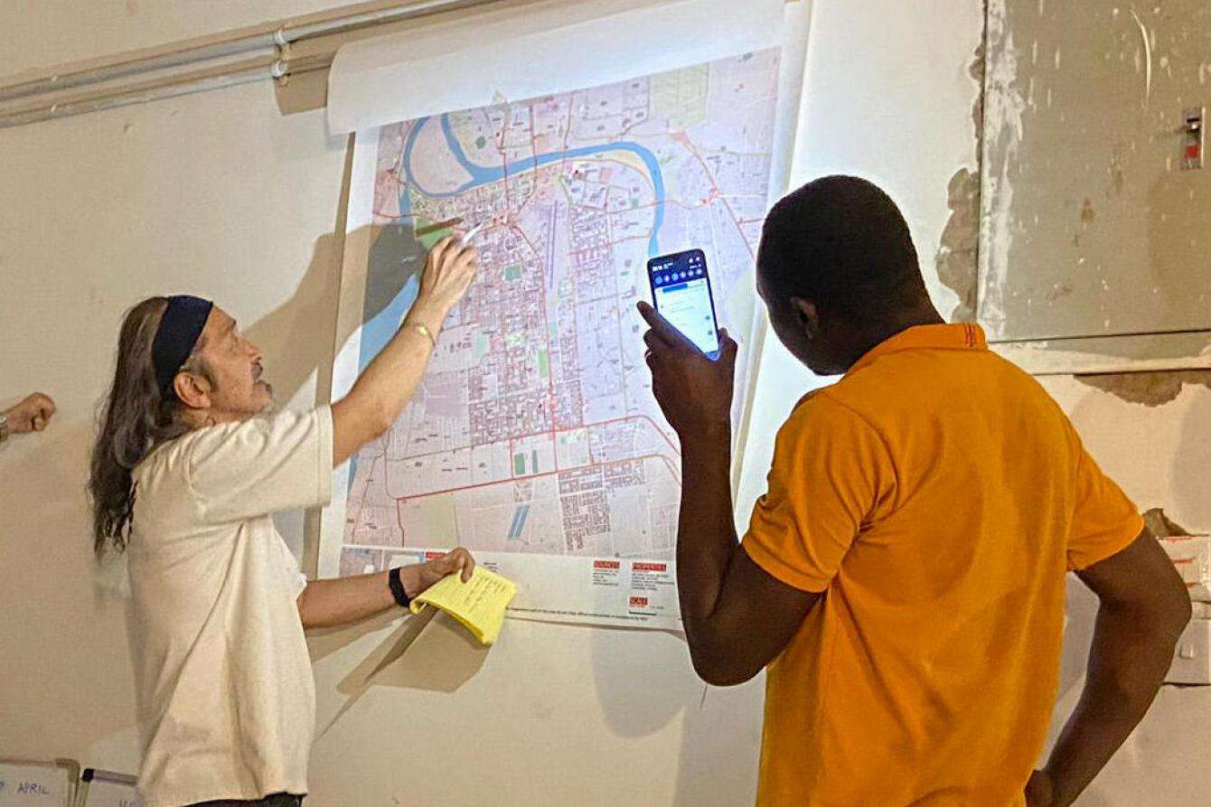MSF team looks at a map in a briefing held while sheltering in a bunker in Khartoum, Sudan