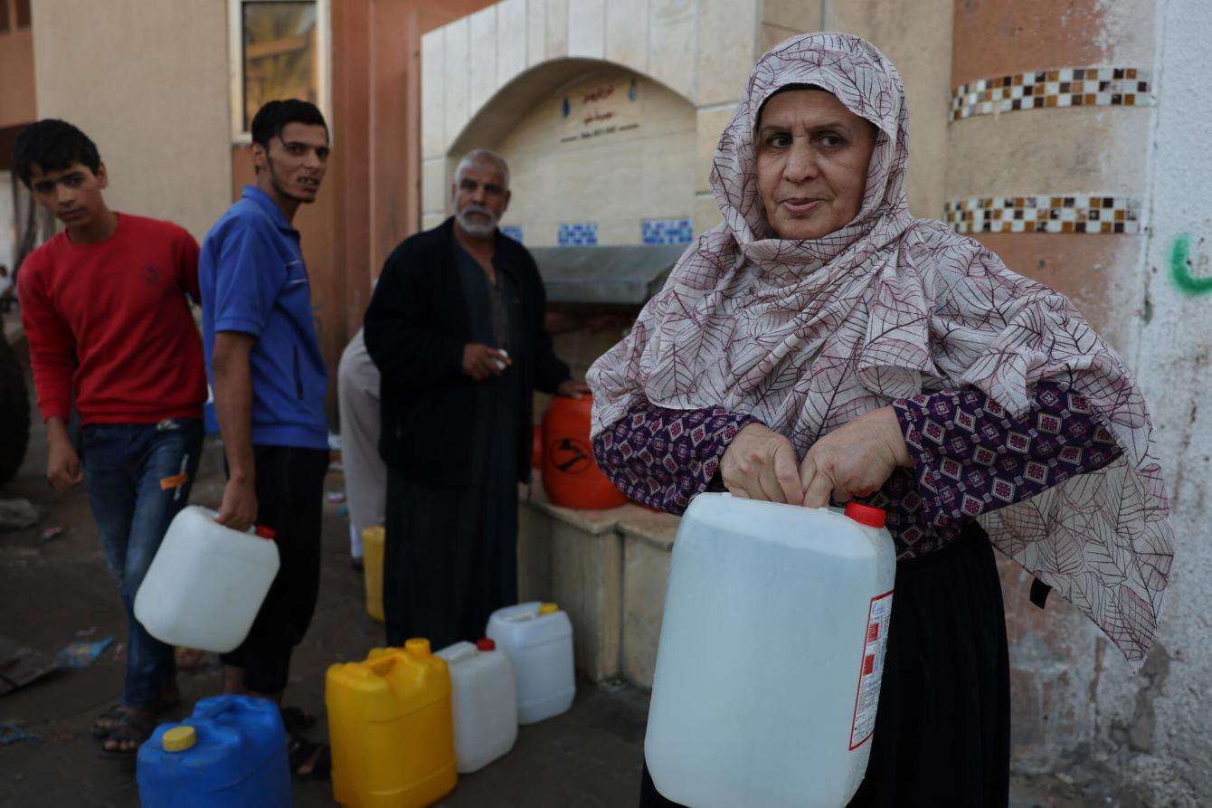 A Palestinian woman holds a jug of water after filling it in Gaza during Israeli siege