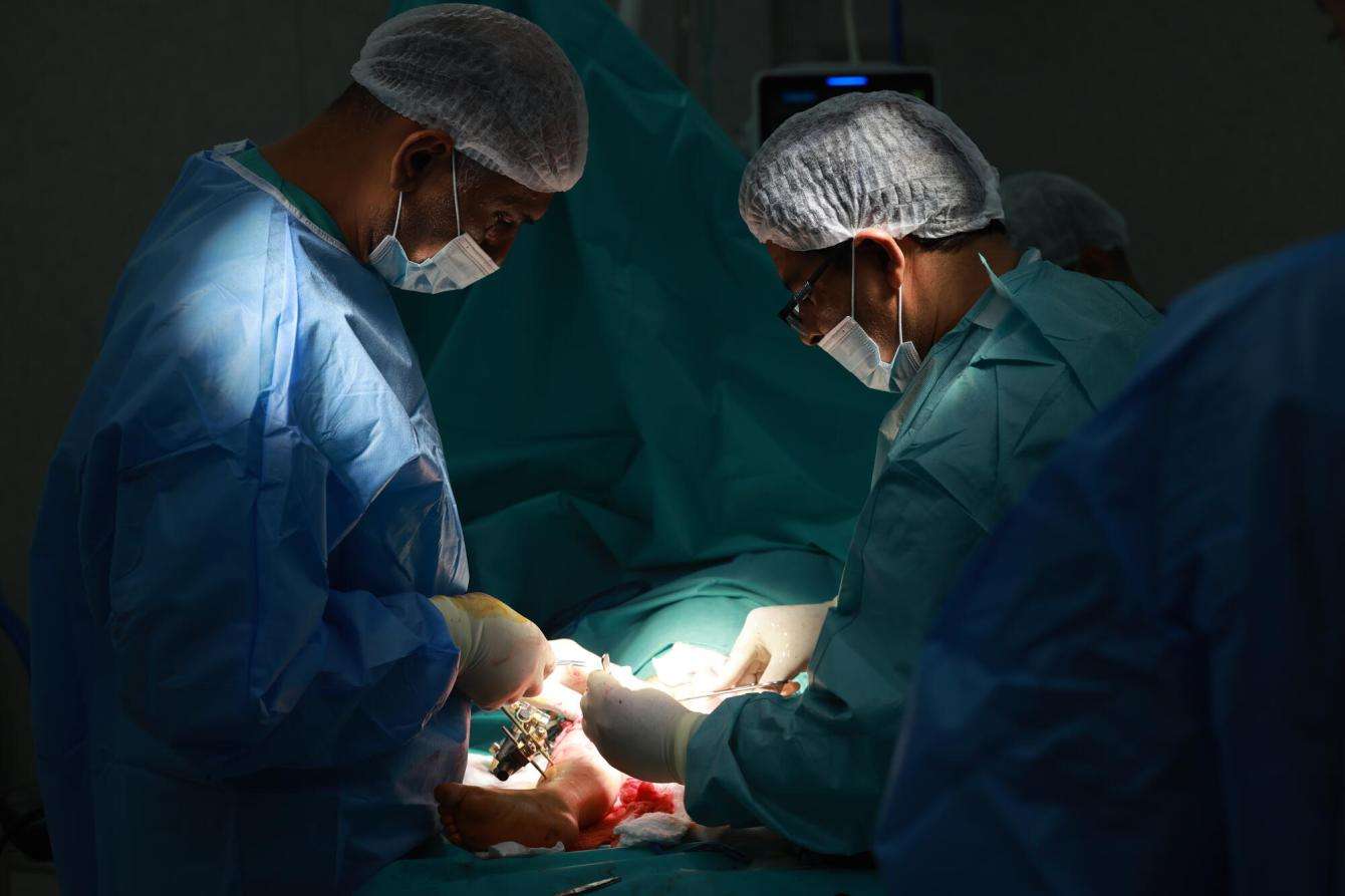 Doctors perform surgery on a patient in a dark room at Nasser Hospital in Gaza