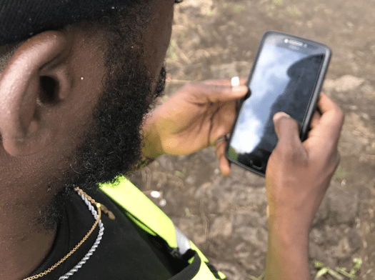 An MSF surveyor looks at his phone while collecting geodata in a displacement camp near Goma, Democratic Republic of Congo