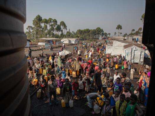 Crowd of displaced people wait to refill water tanks in Lushagala displacement camp near Goma, Democratic Republic of Congo