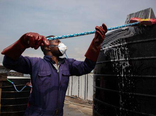 An MSF water and sanitation worker wipes down tanks at water treatment station at Lushagala displacement camp in Democratic Republic of Congo.