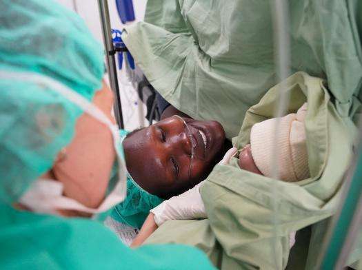 A woman looks at her newborn baby after a cesarean section at  Mundari County Hospital, South Sudan.