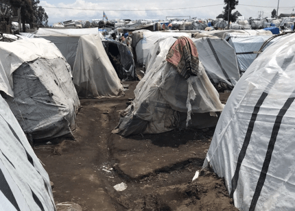 Muddy trenches between makeshift tents made of plastic sheeting in displacement camp near Goma, Democratic Republic of Congo.