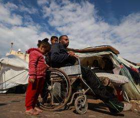 An injured Palestinian man in a wheelchair returns to his tent.